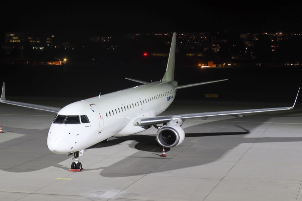A Marathon Airlines Embraer E195 on a floodlit ramp at night