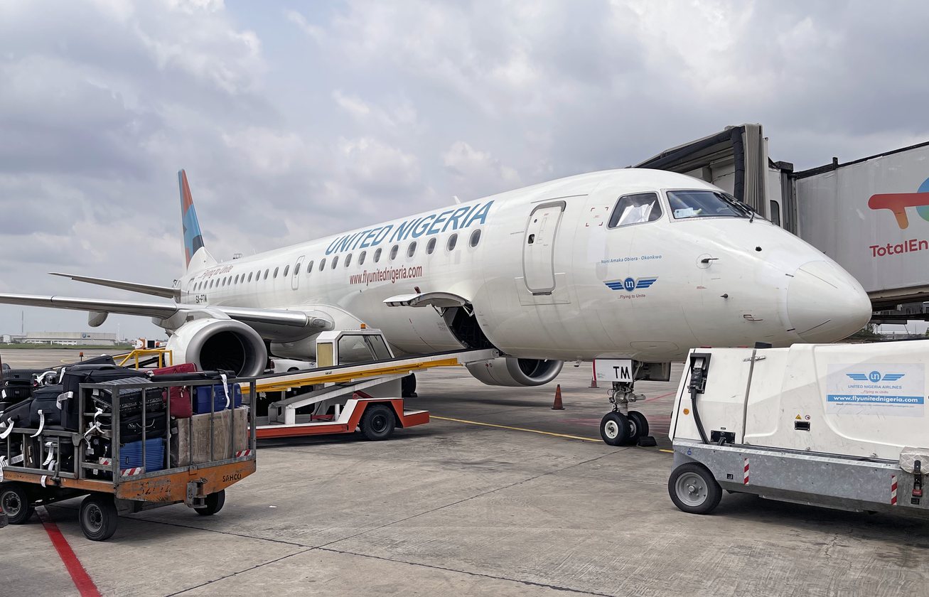 Embraer aircraft in United Nigeria livery at a stand with ground service equipment